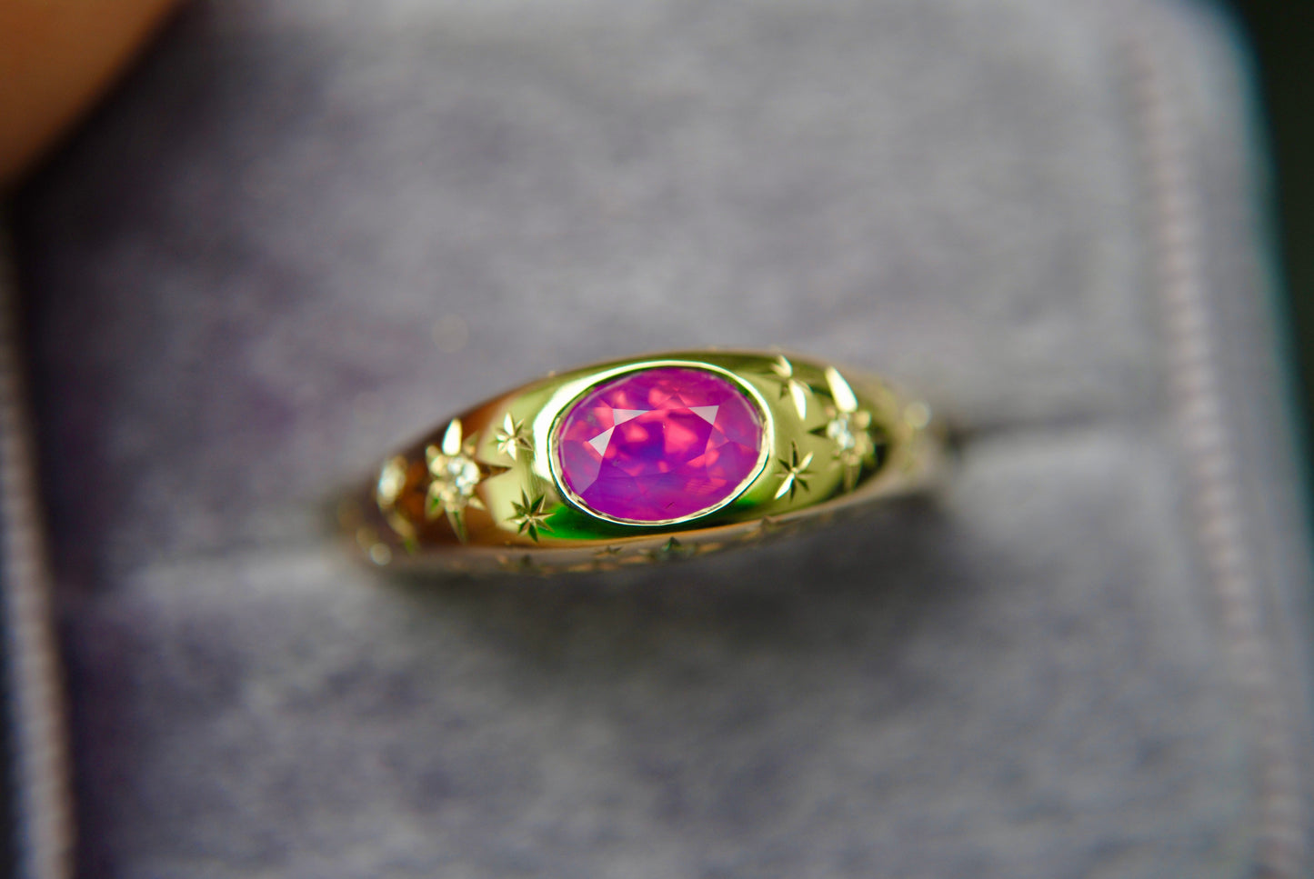 Gold ring with a pink gemstone on a gray background