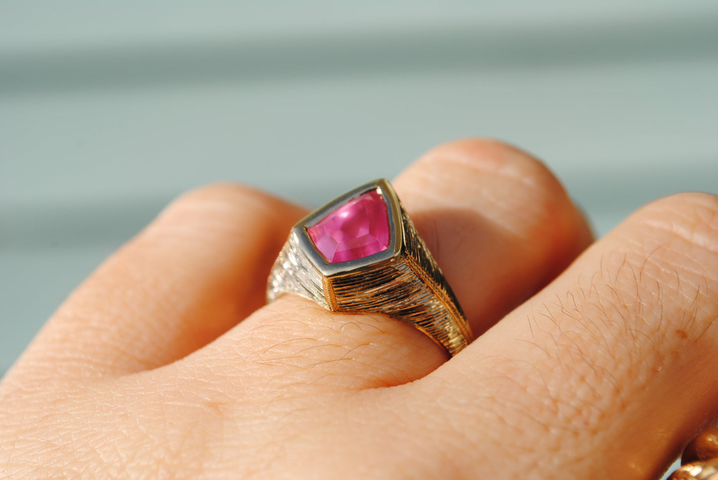 Gold ring with a pink gemstone on a blurred background