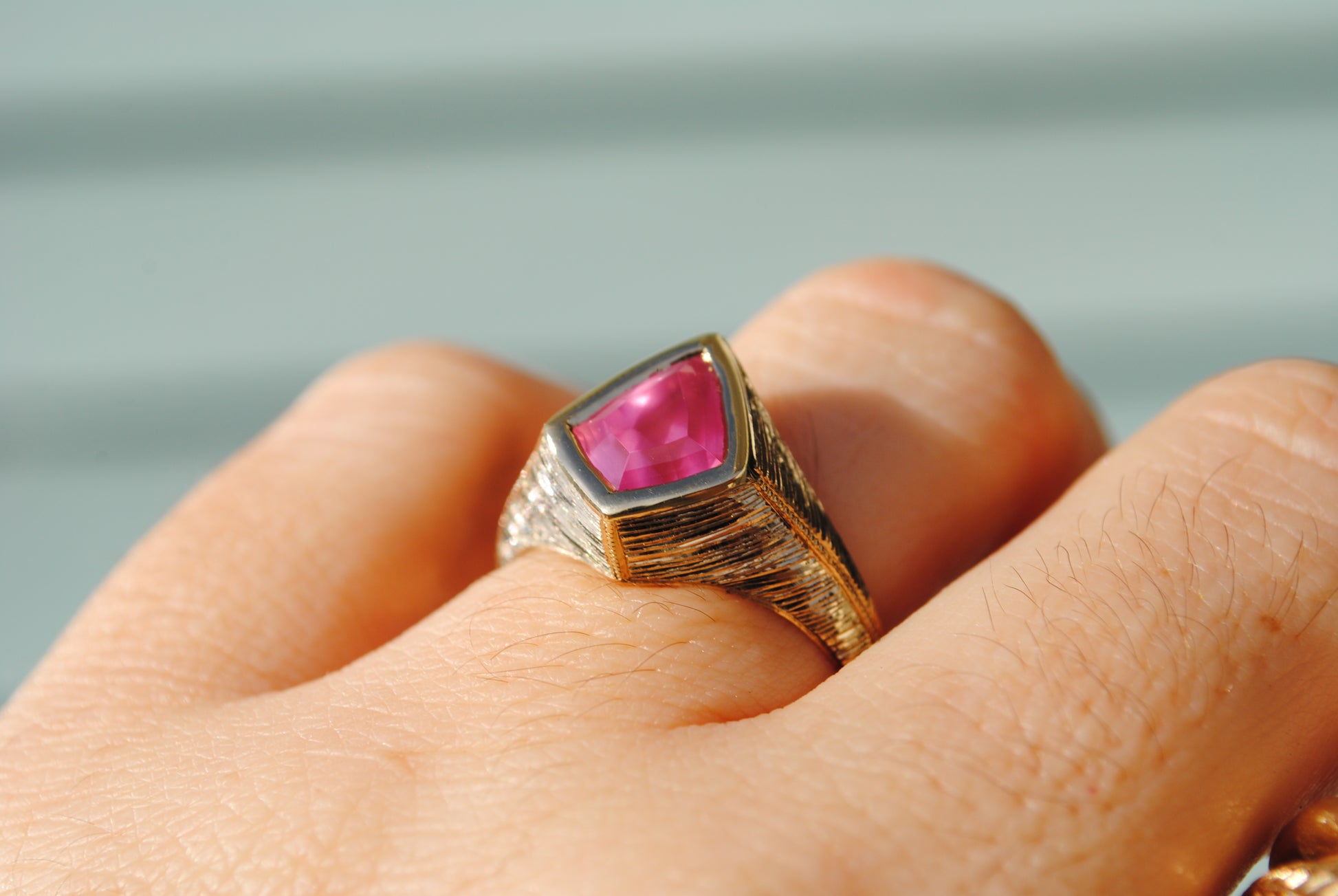 Gold ring with a pink gemstone on a blurred background