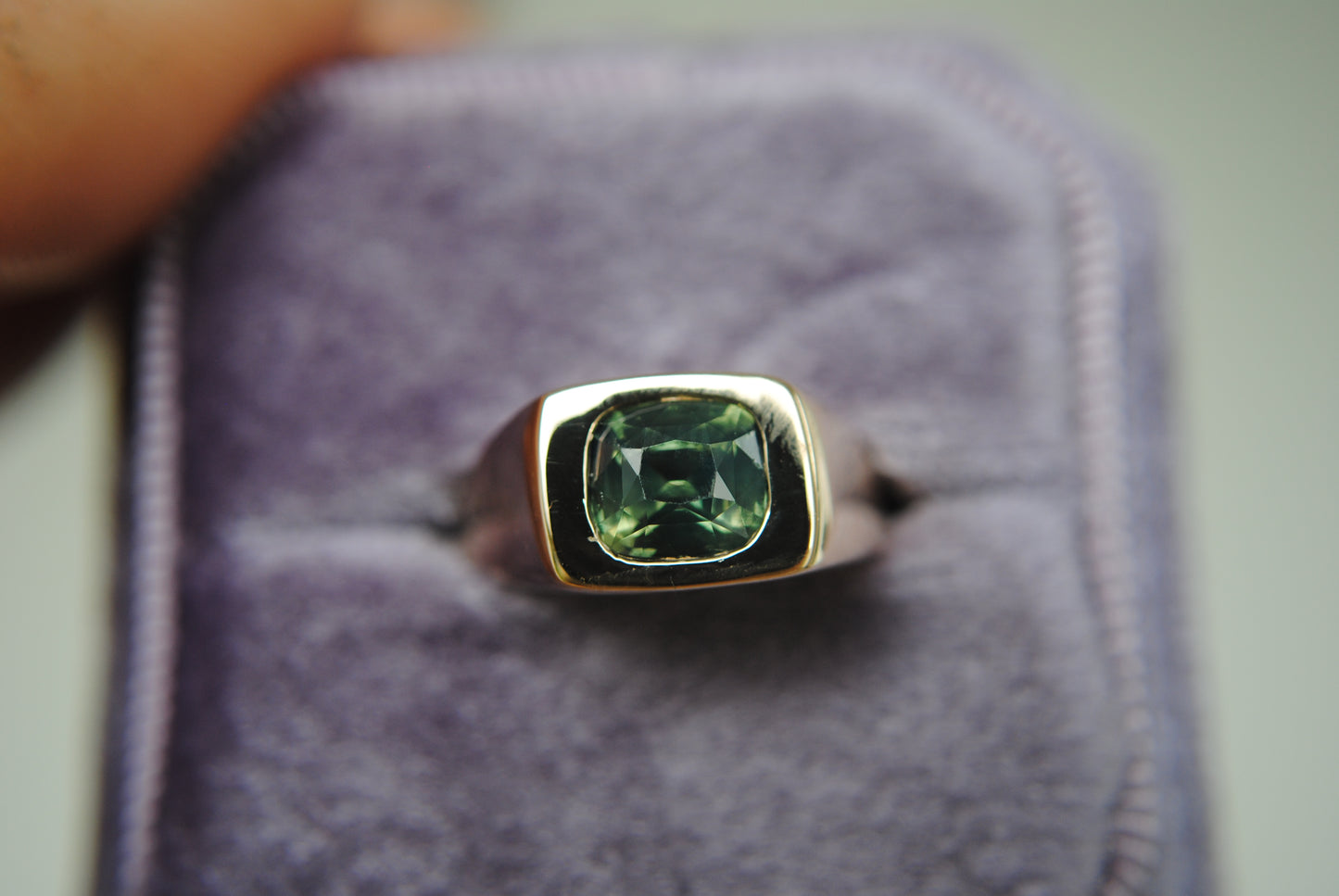Ring with a green gemstone on a gray background