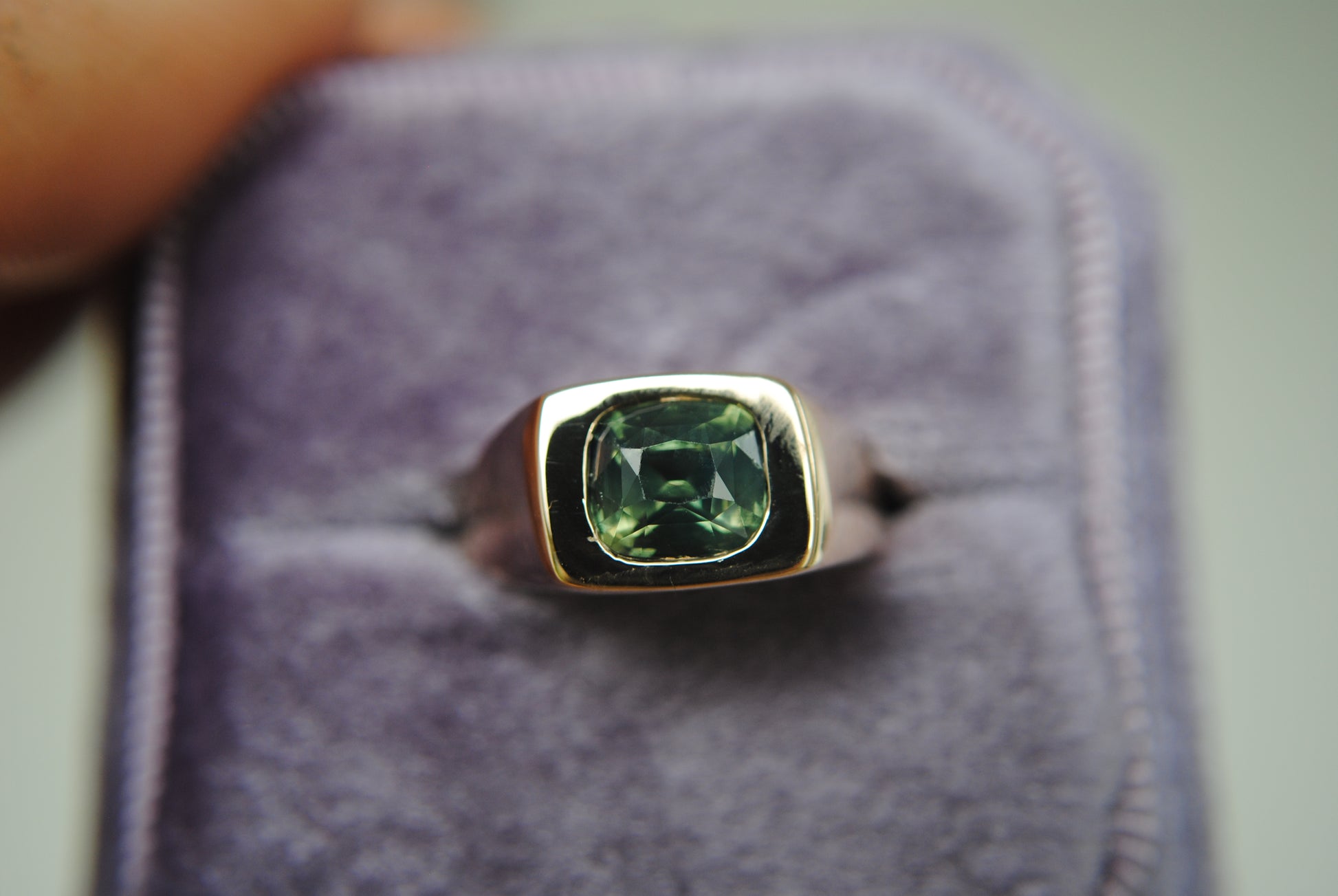 Ring with a green gemstone on a gray background
