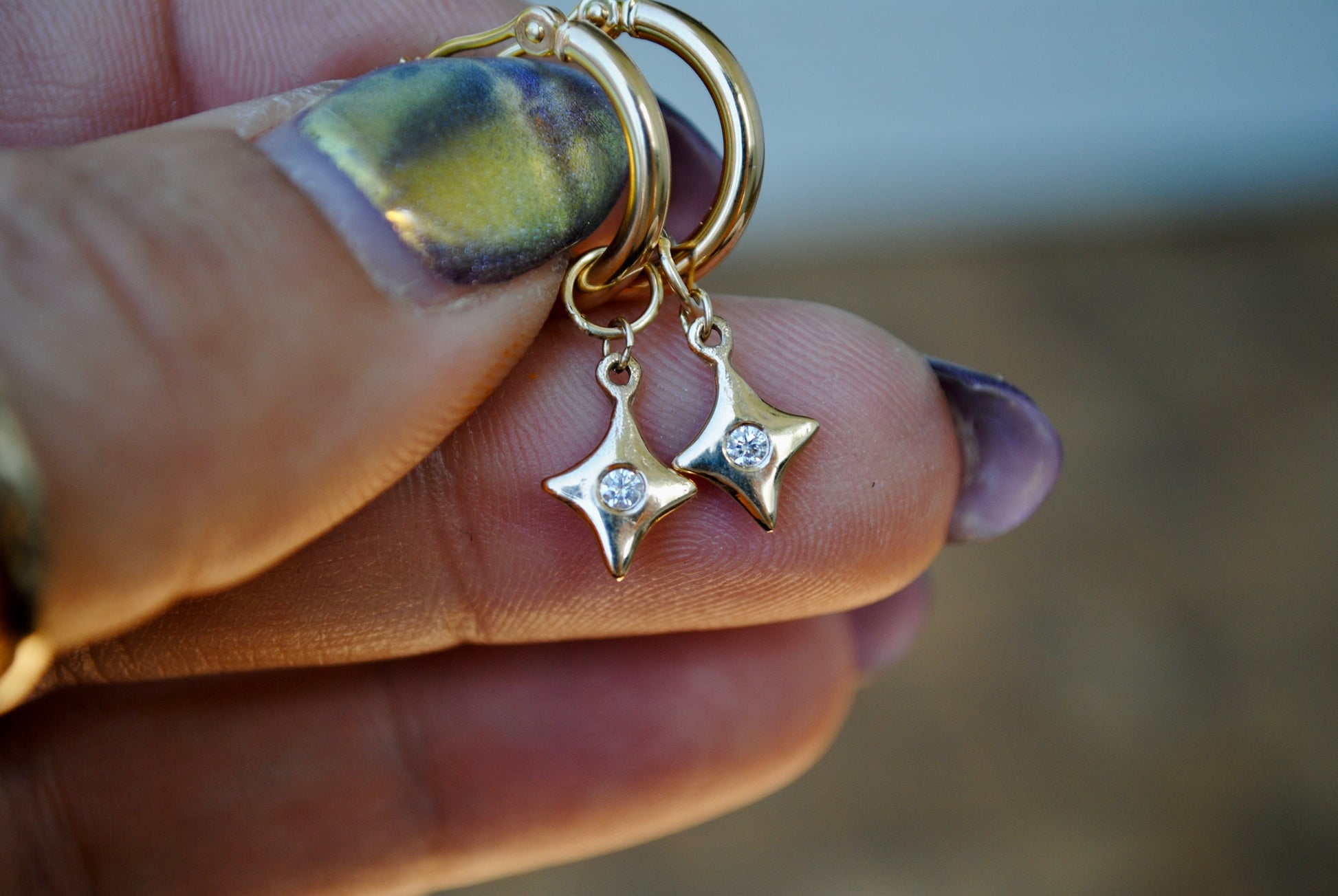 Gold keychain with star-shaped charms held by a hand with purple nail polish.