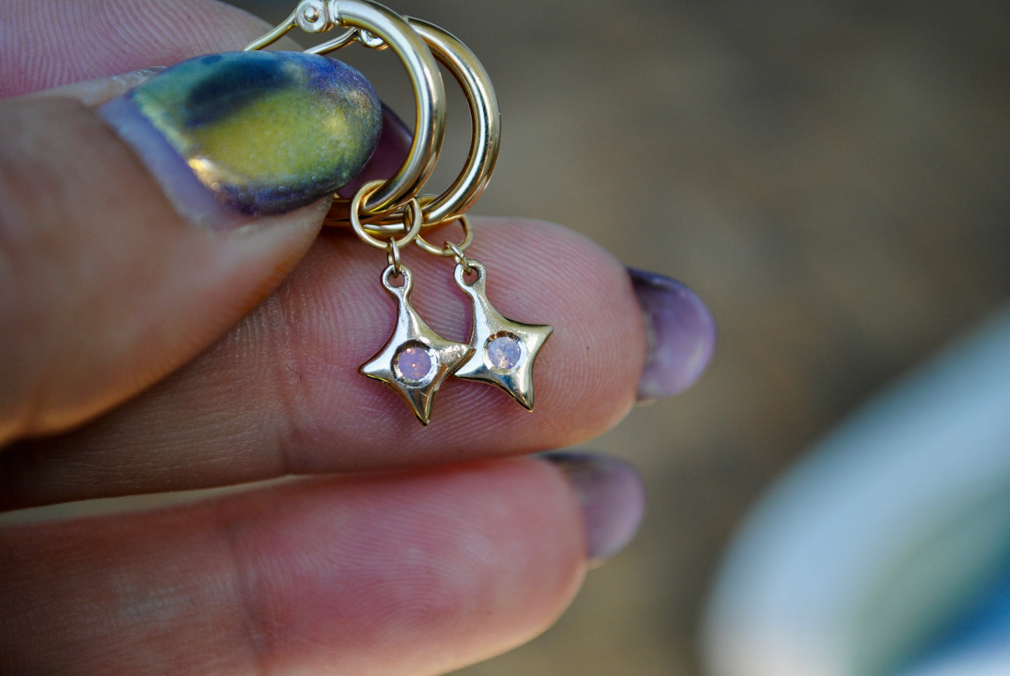 Gold charm with star and moon design held between fingers