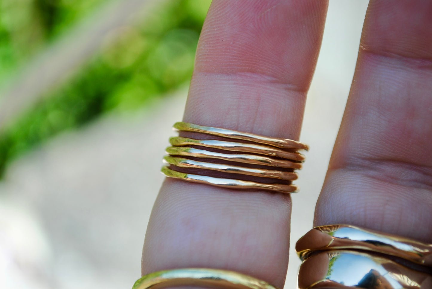 Gold rings on a finger with a blurred natural background