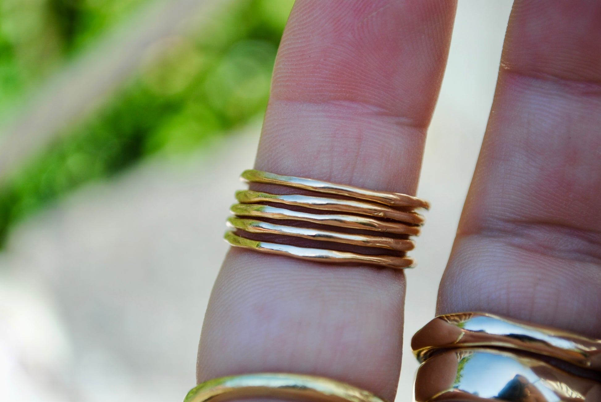 Gold rings on a finger with a blurred natural background