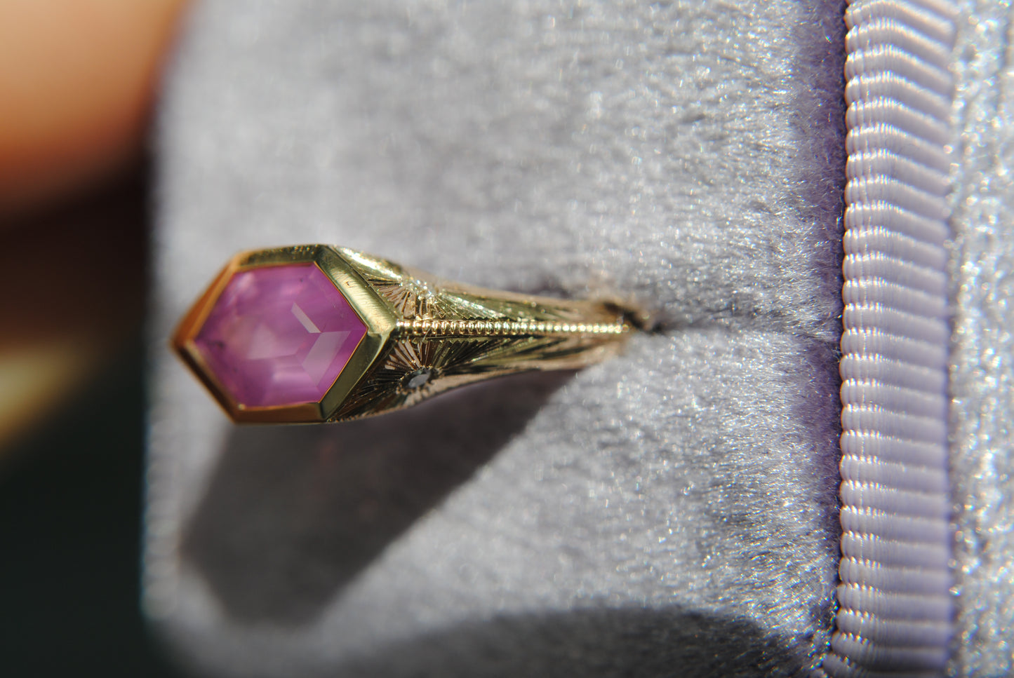 Gold ring with a pink gemstone in an open jewelry box