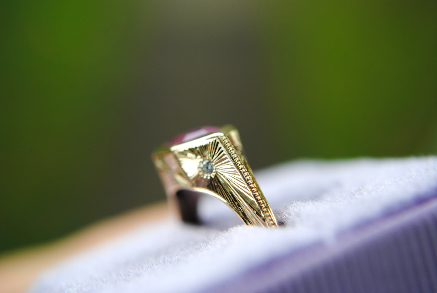 Gold ring with a diamond on a white surface against a blurred green background