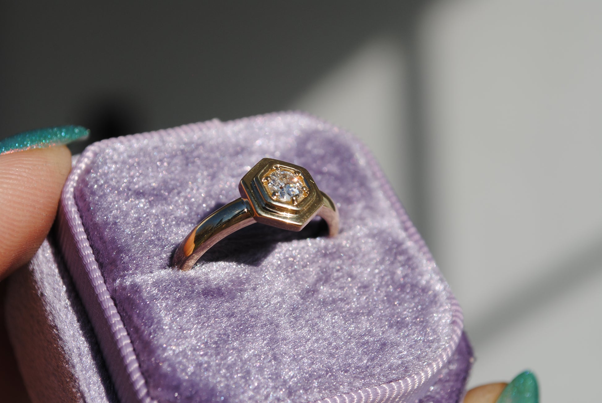Gold ring with a diamond on a purple cushion