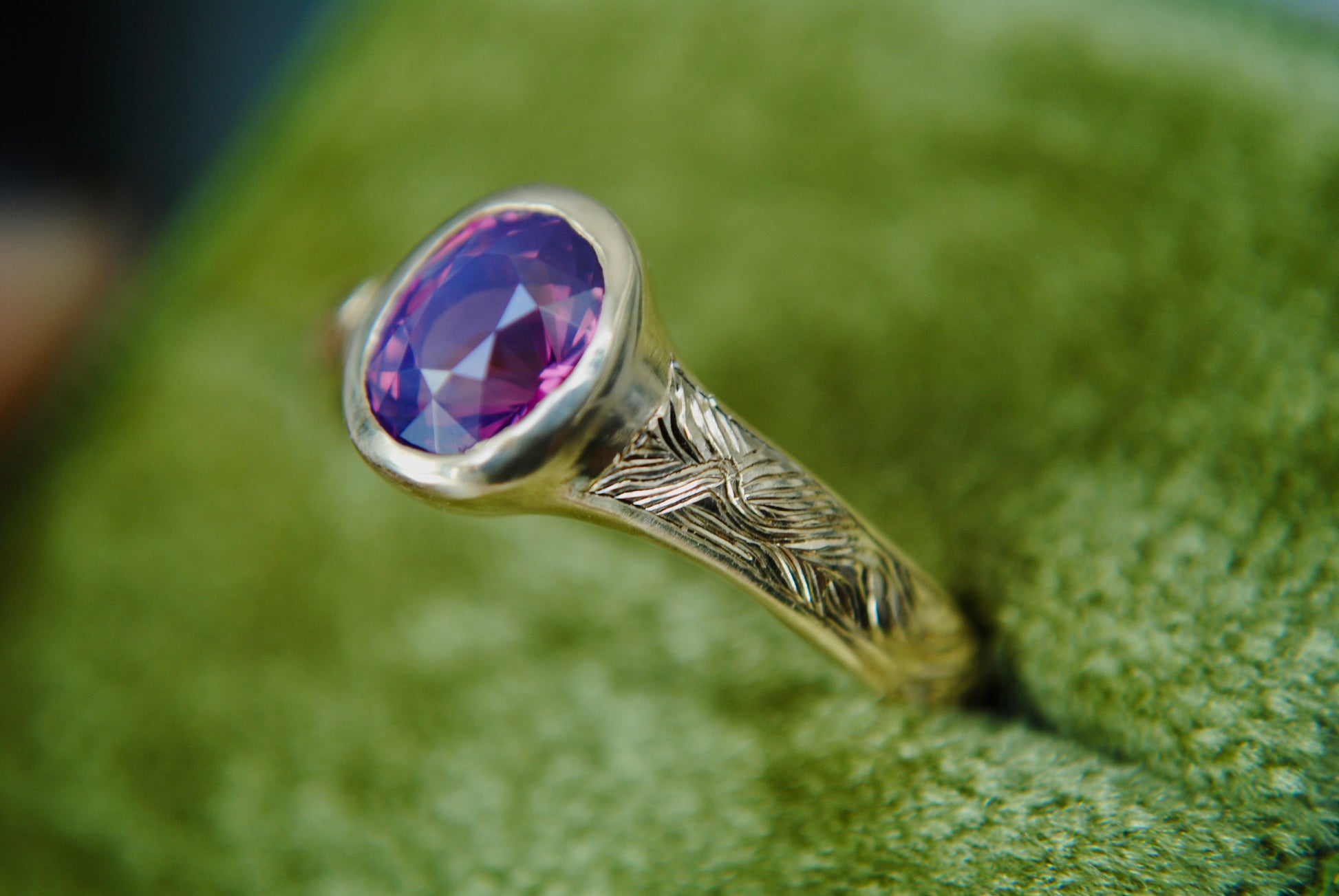 Gold ring with a purple gemstone on a green textured background