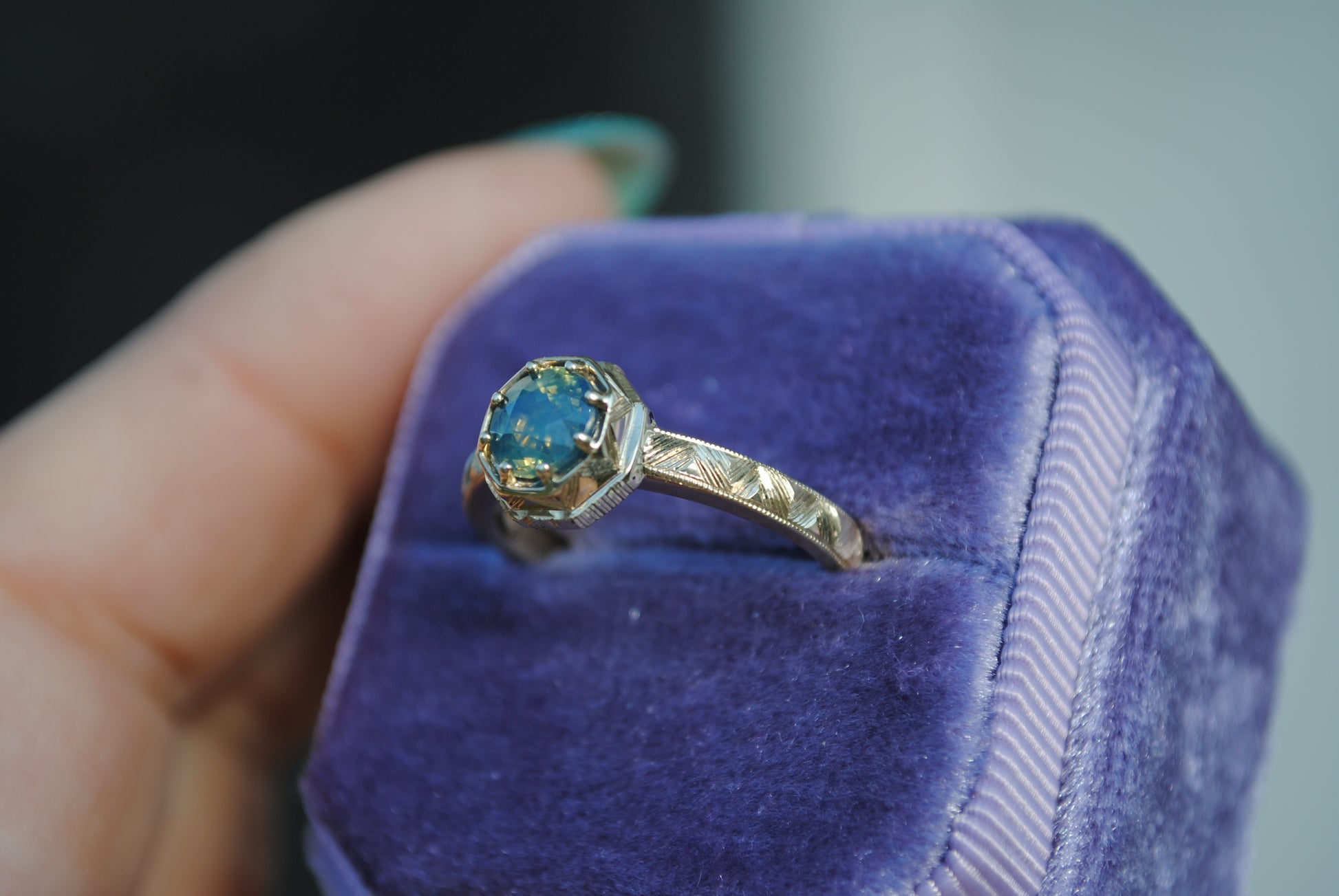 Gold ring with a blue gemstone in a purple velvet box