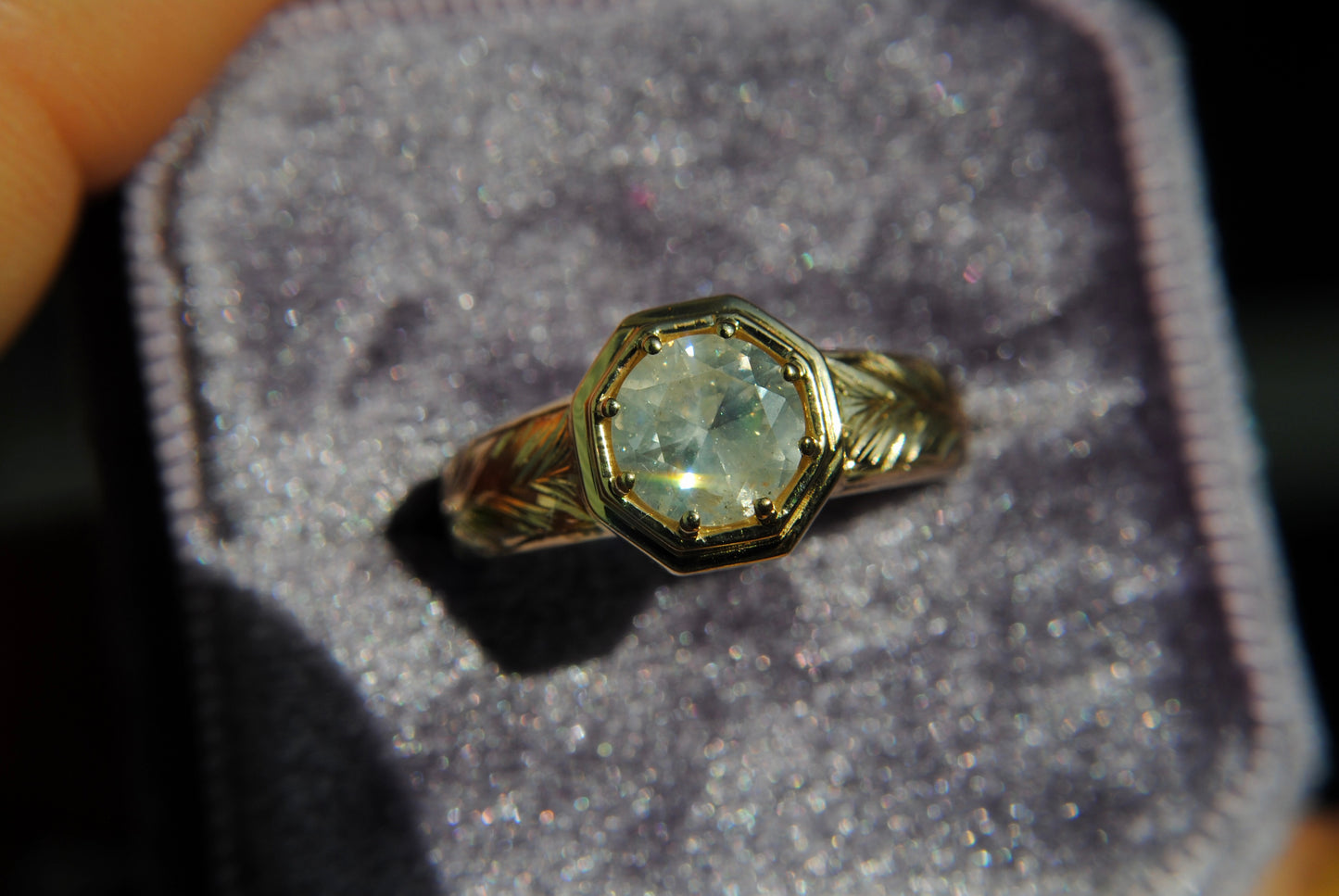 Gold ring with a diamond on a gray cushion