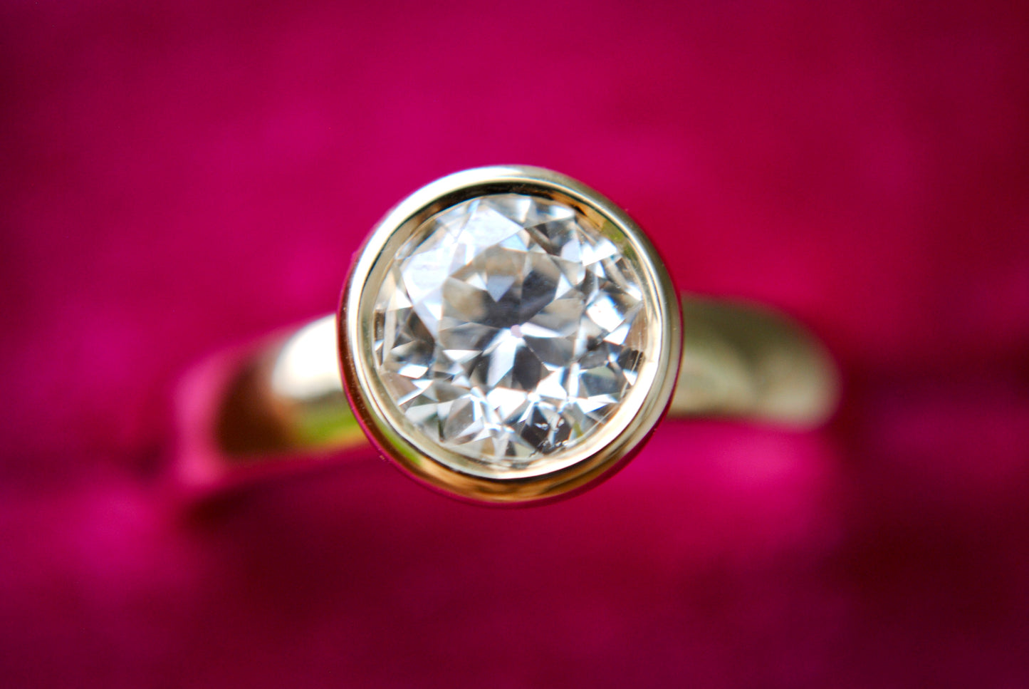 Gold ring with a diamond on a pink background