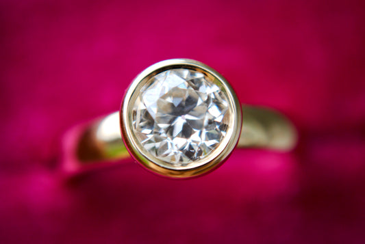 Gold ring with a diamond on a pink background