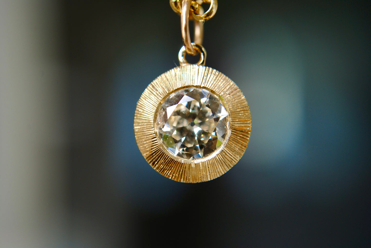 Gold pendant with a diamond on a blurred background