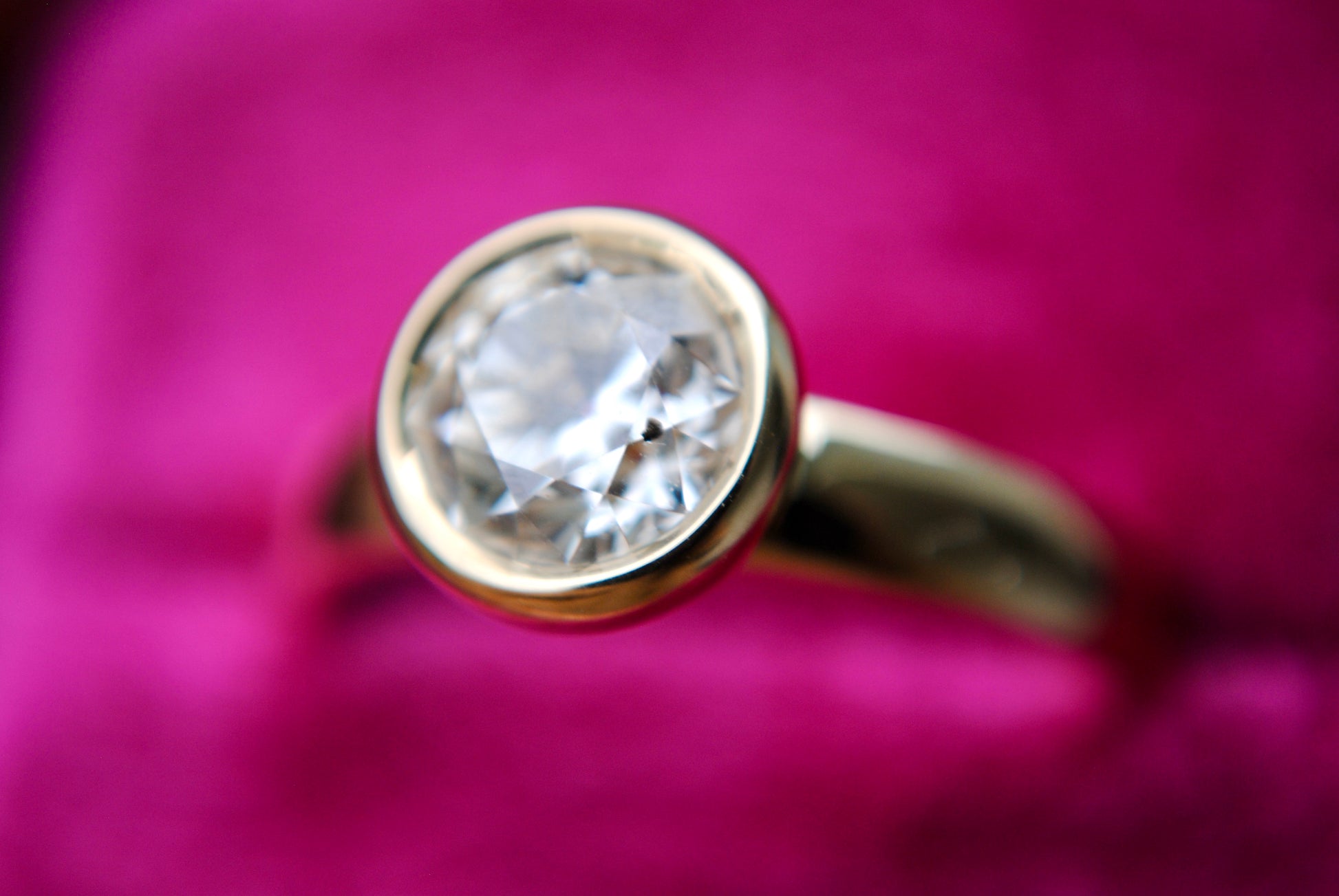 Gold ring with a diamond on a pink background