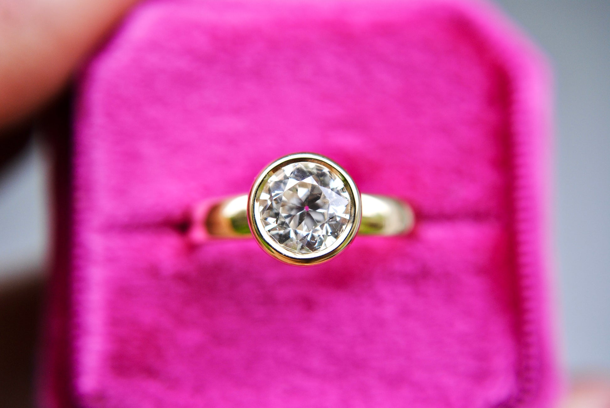 Gold ring with a diamond on a pink velvet cushion