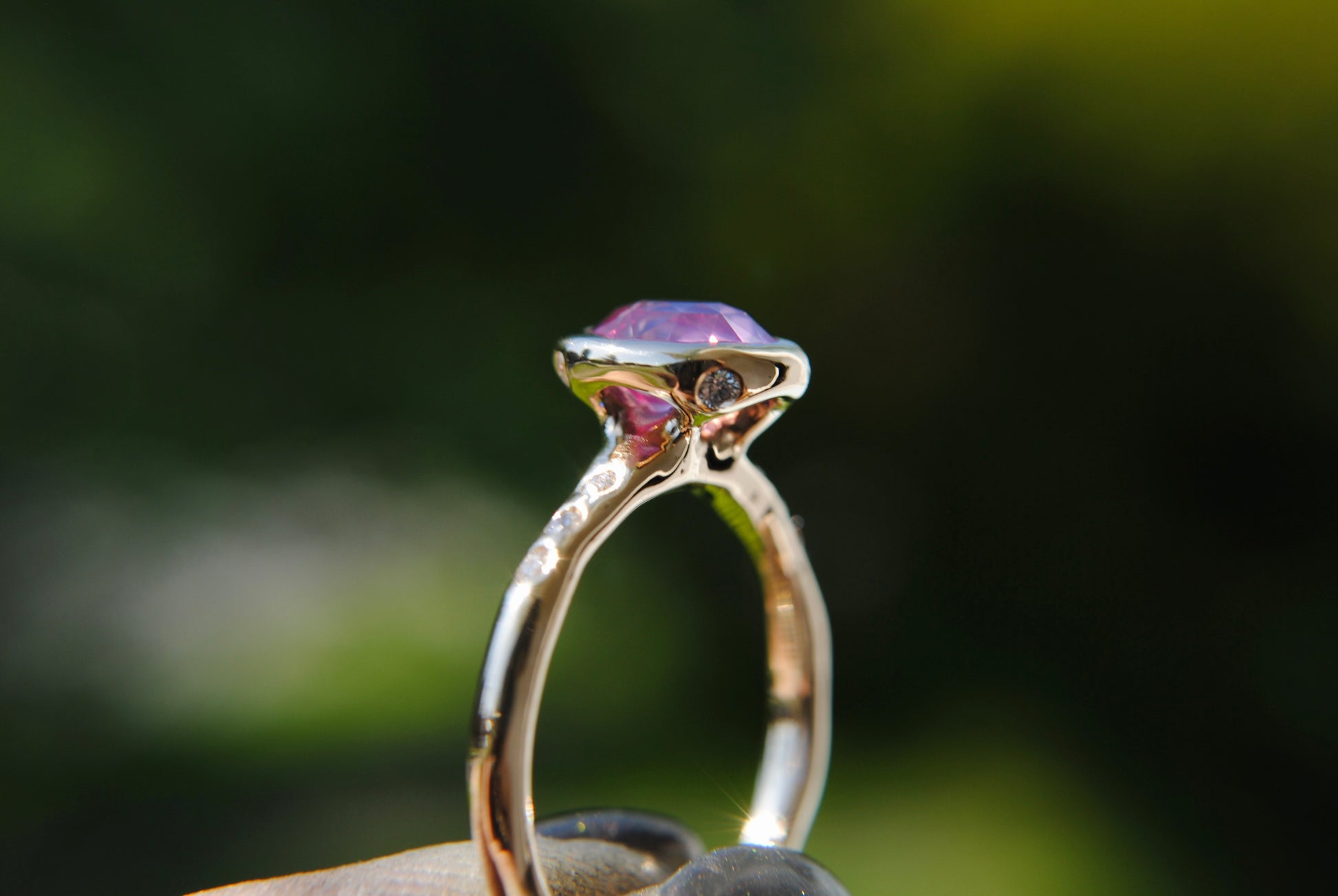 Gold ring with a purple gemstone held in hand against a blurred natural background