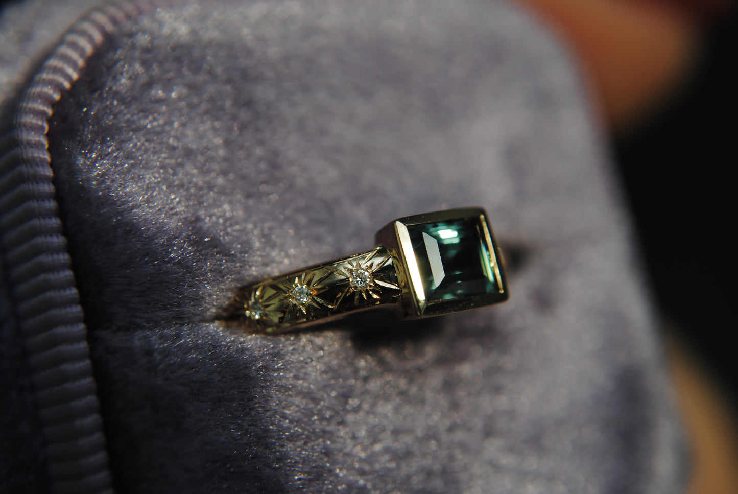 Gold ring with a green gemstone on a textured surface