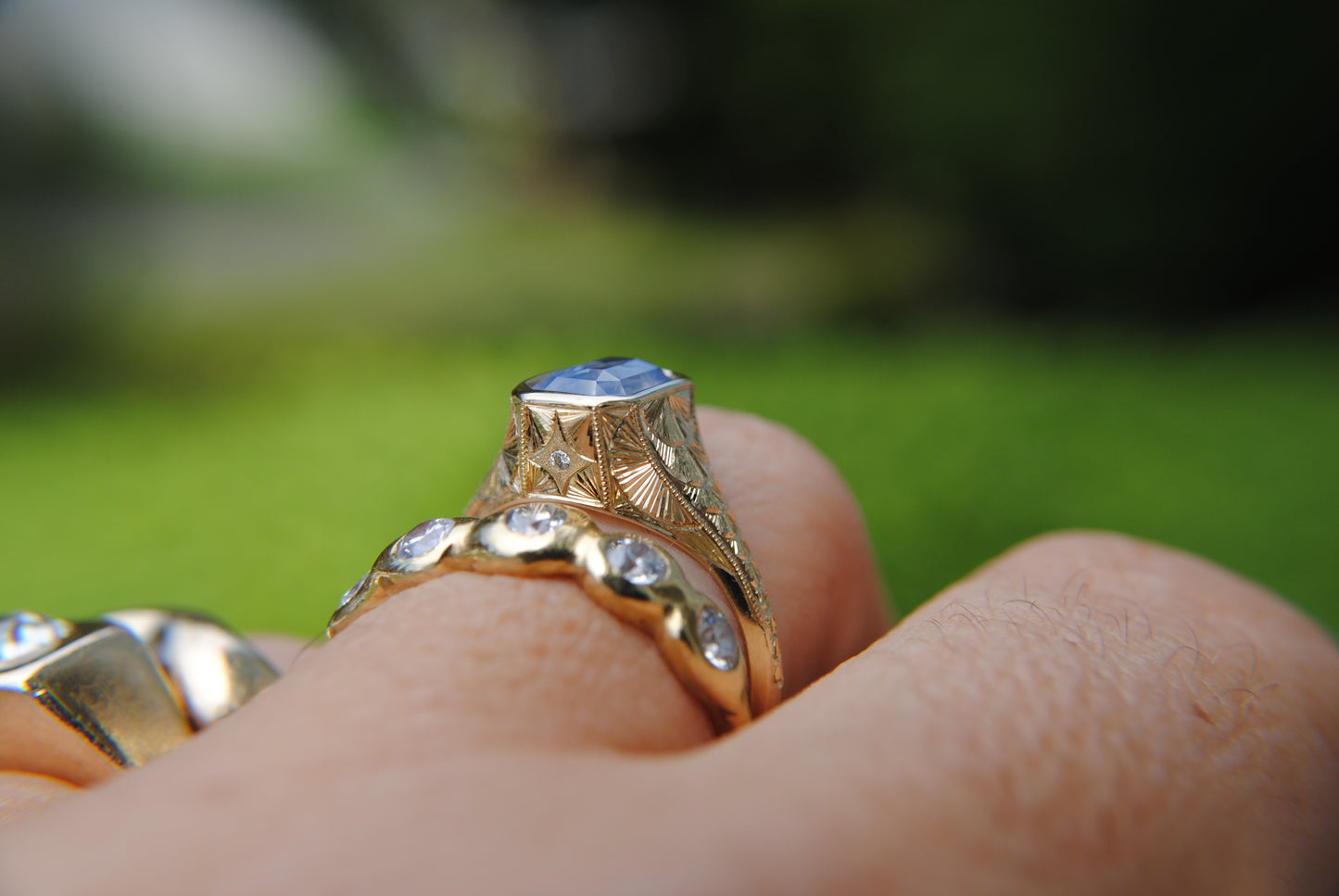 Gold ring with a diamond on a finger against a blurred green background