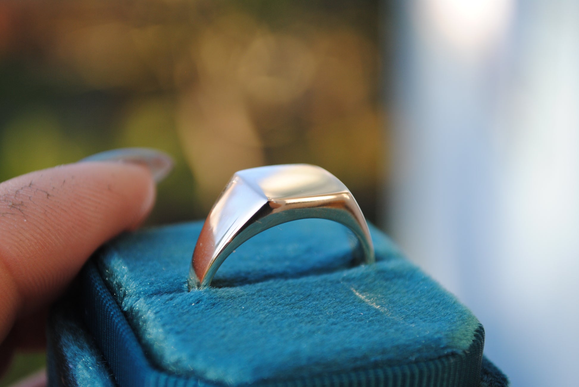 Silver ring on a blue cushion with a blurred background