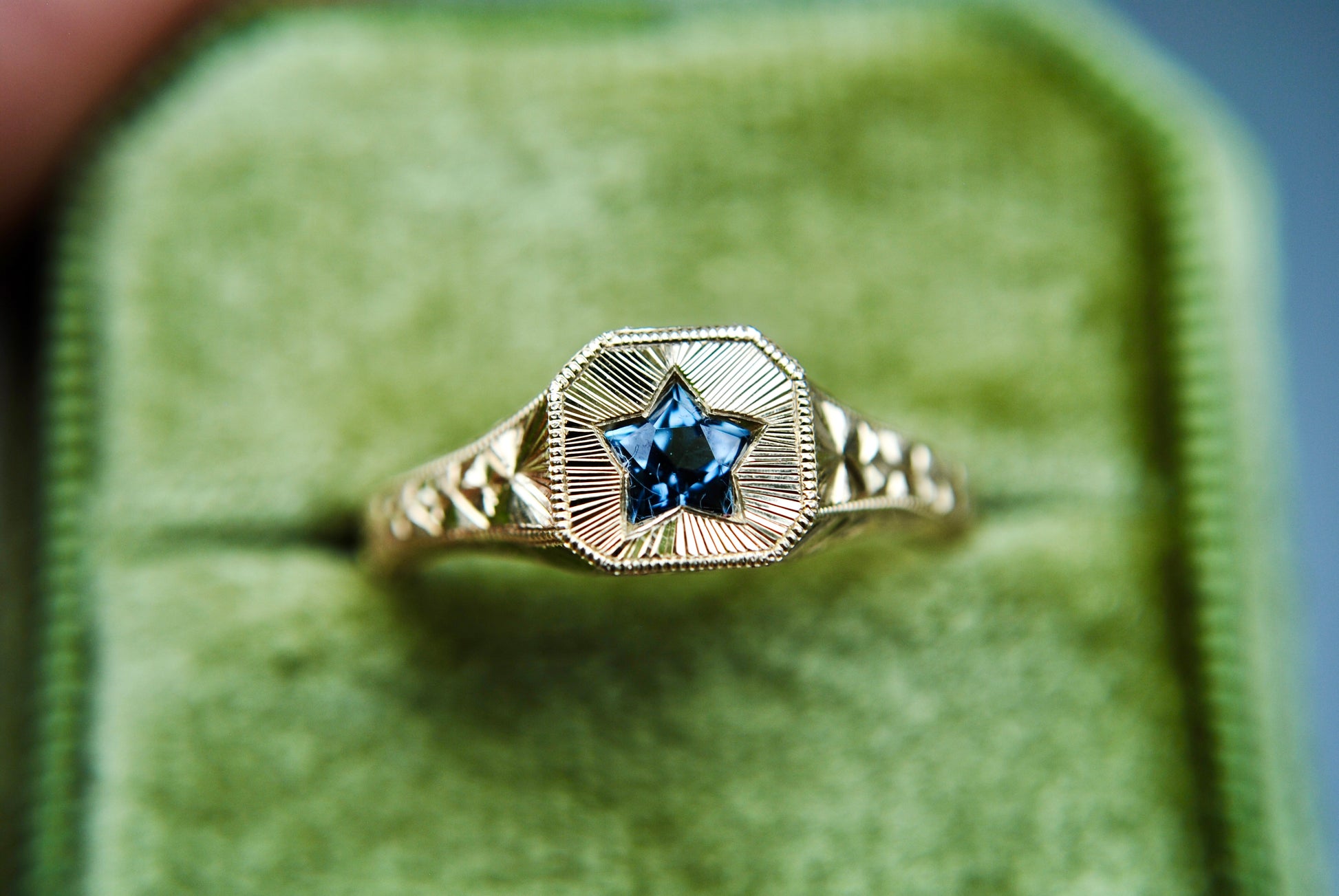 Gold ring with a blue gemstone on a green cushion