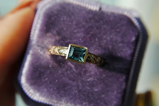 Gold ring with a green gemstone in a purple jewelry box
