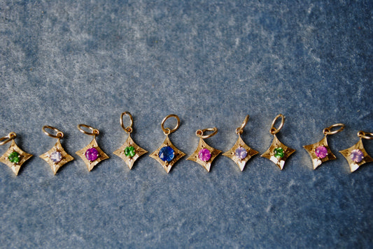Star-shaped gold pendants with colorful gemstones on a textured blue background