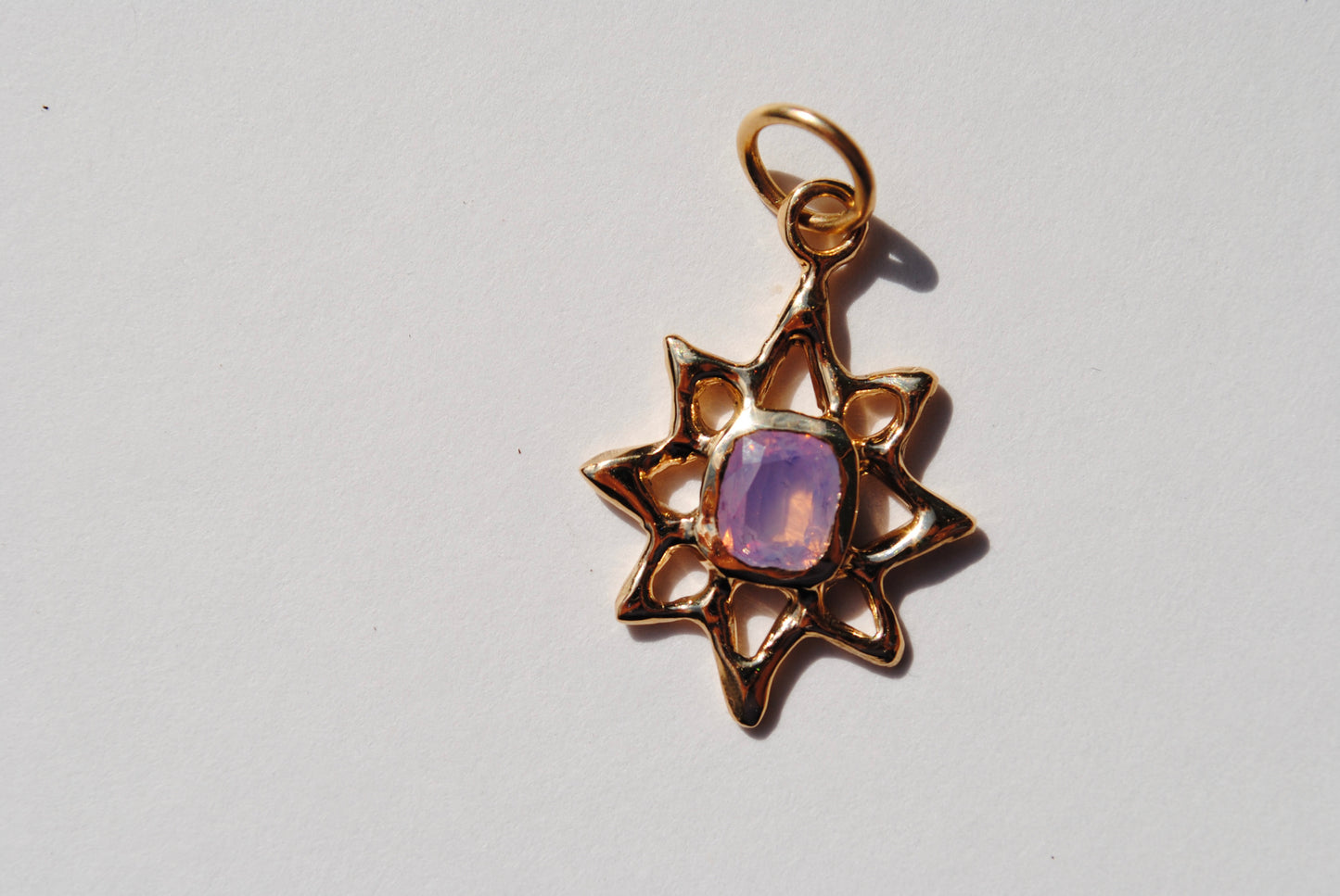 A gold lucky star charm with a central sapphire