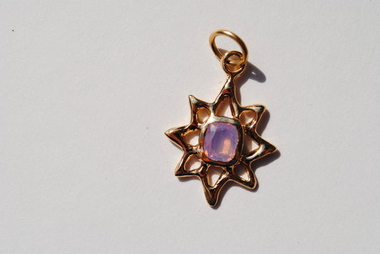 A gold lucky star charm with a central sapphire
