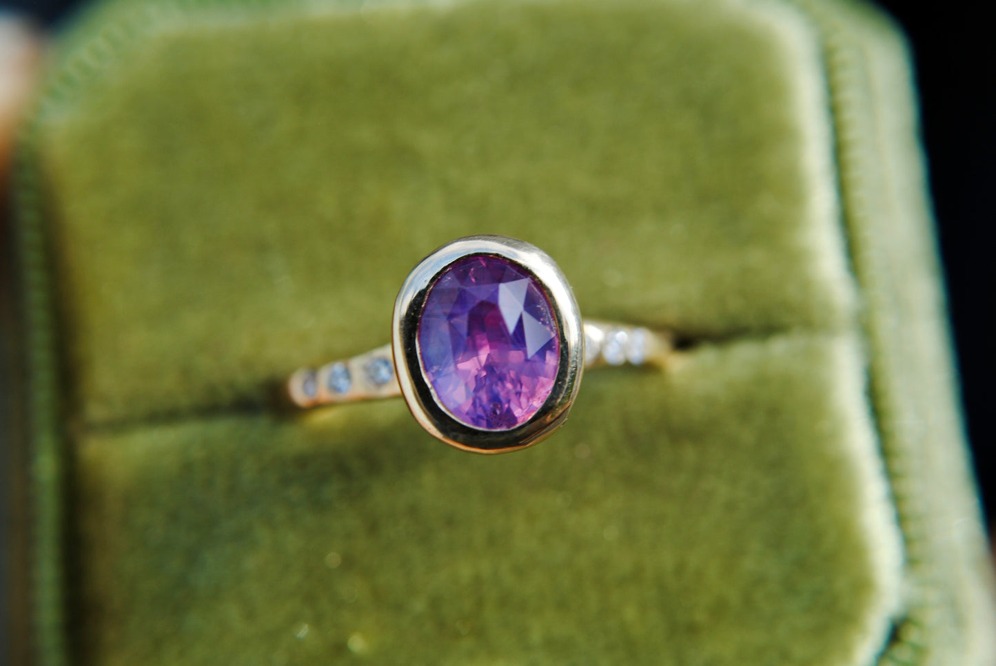 Gold ring with a purple gemstone on a green velvet background