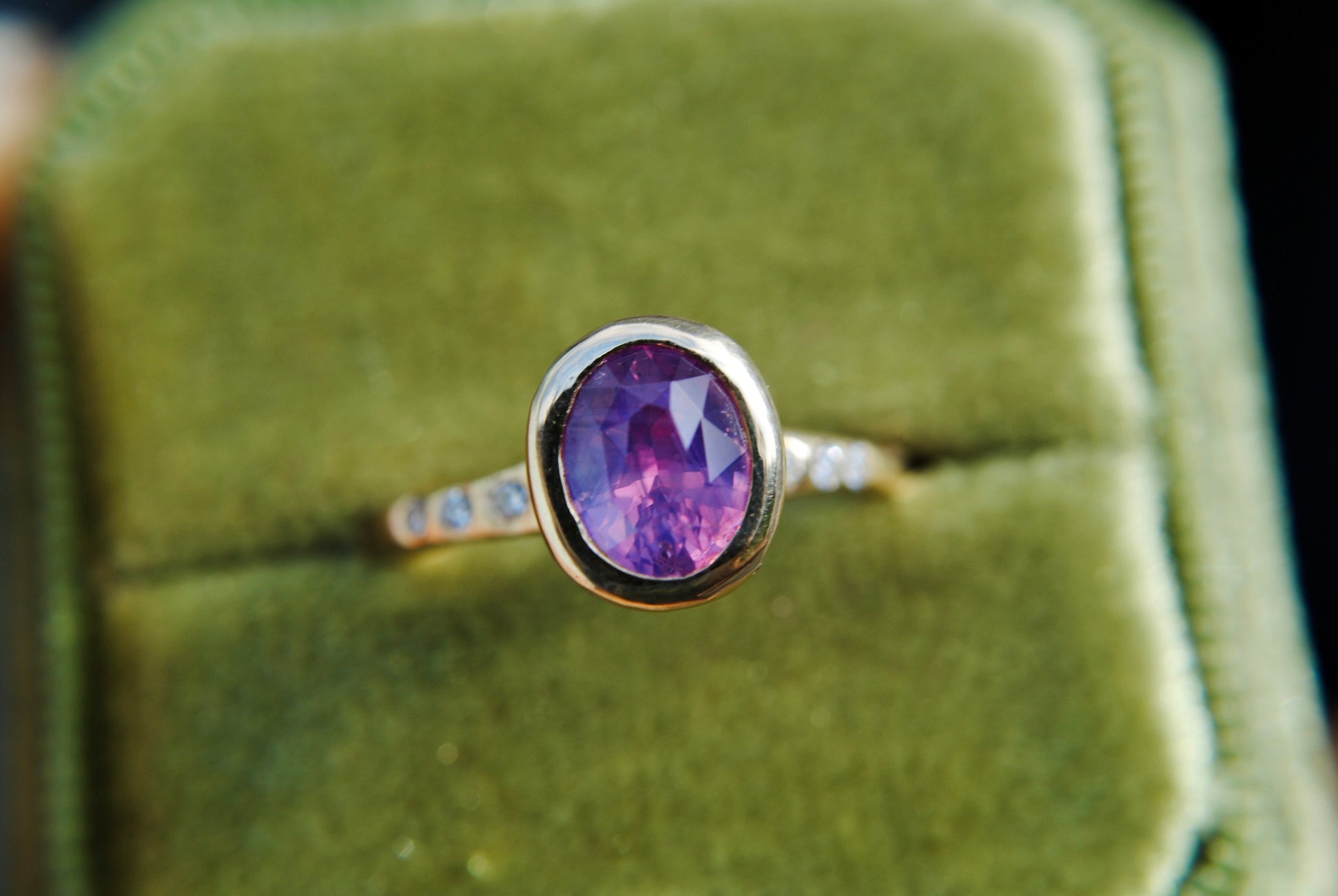 Gold ring with a purple gemstone on a green velvet background