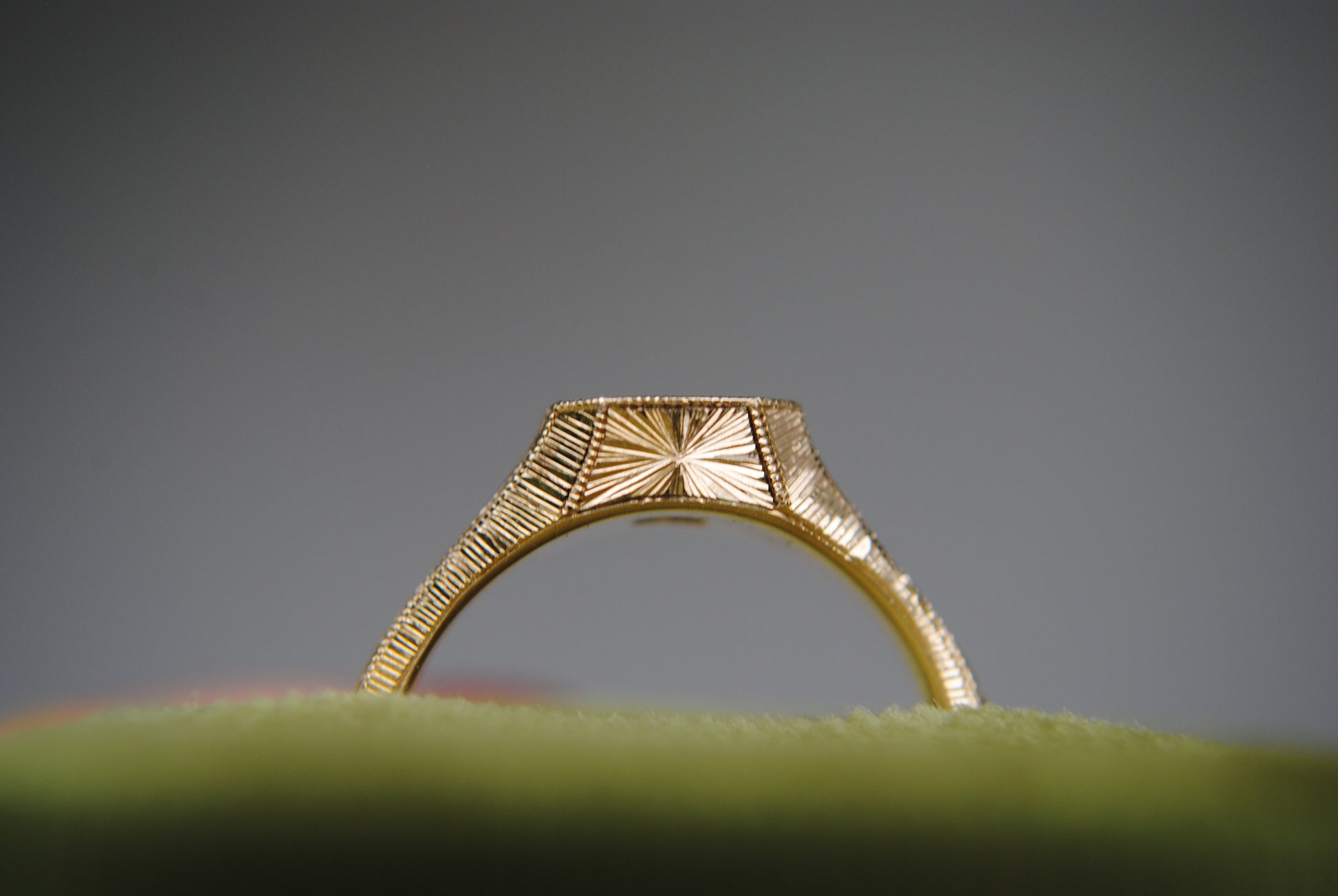 Gold ring with intricate design on a gray background