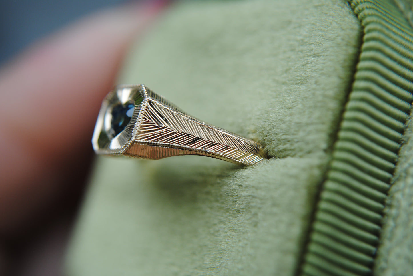 Silver ring with feather design on a green cushion
