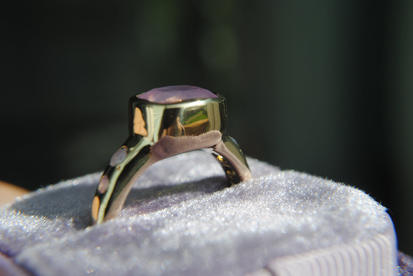 side profile of gold ring with pink stone in a box