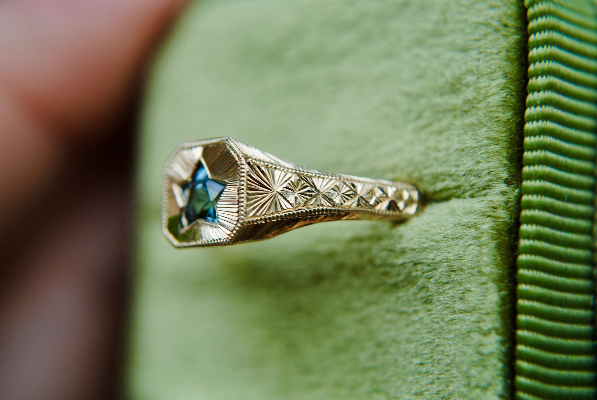 Gold ring with star design on a green fabric background