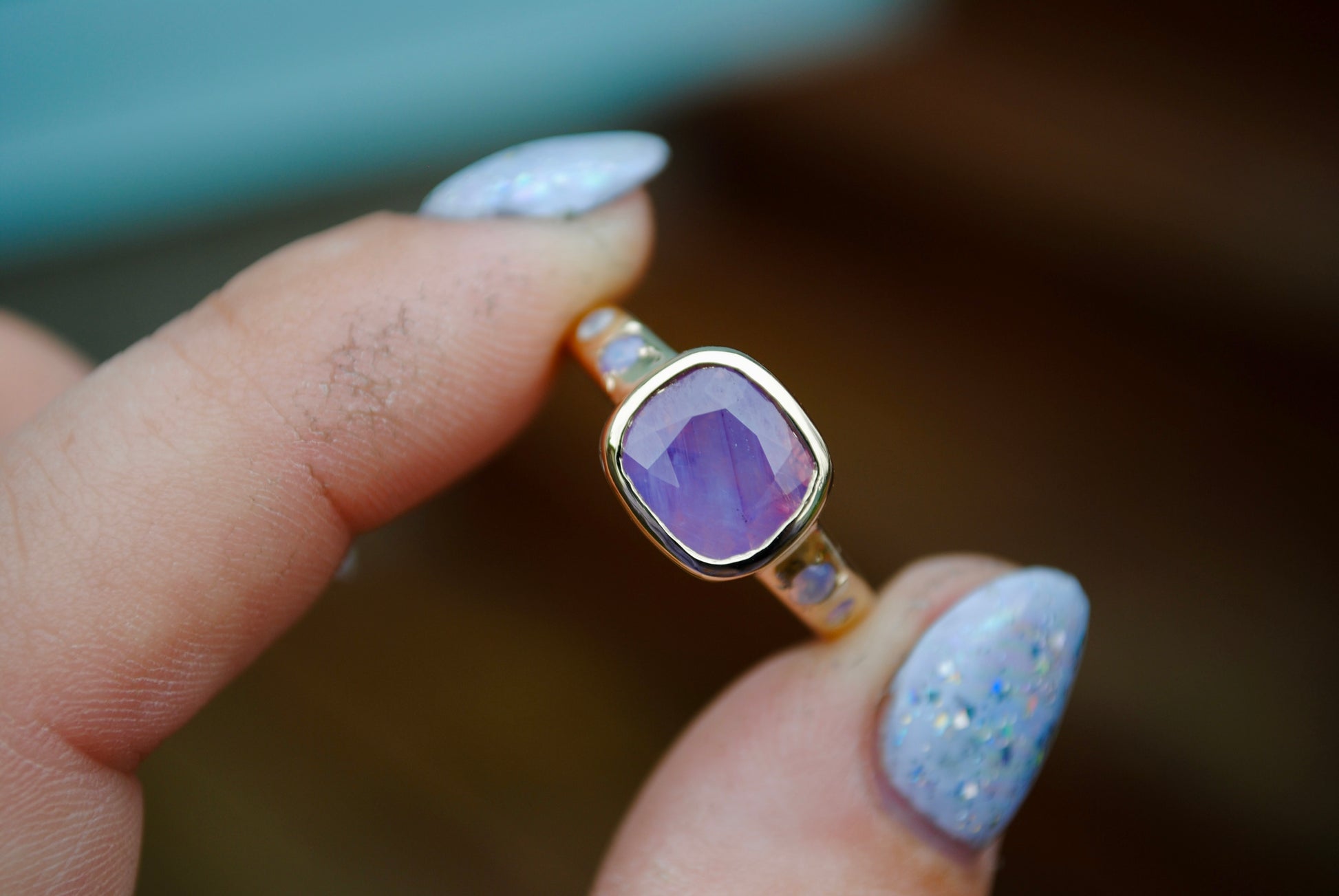 large sapphire between 2 fingers with blurred background