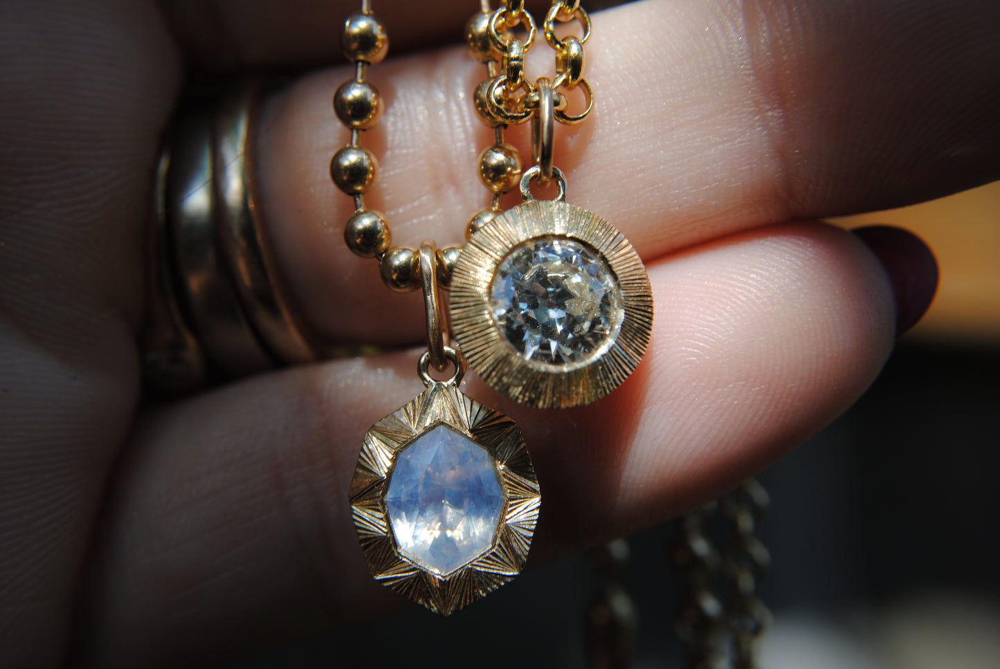 Gold necklace with pendant held by a hand